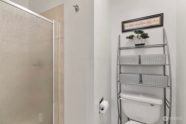 bathroom with a shower with door and toilet