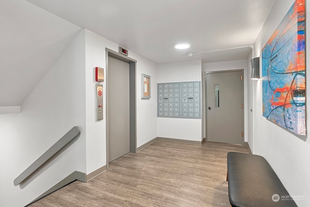 hallway with light hardwood / wood-style floors, mail boxes, and elevator