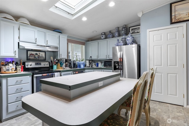 kitchen with crown molding, stainless steel appliances, vaulted ceiling with skylight, and a kitchen island