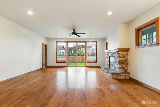 unfurnished living room featuring a fireplace, light hardwood / wood-style floors, and ceiling fan