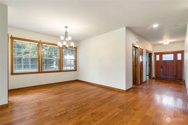 unfurnished room with a notable chandelier and wood-type flooring