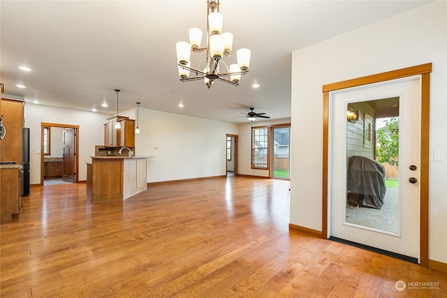 interior space with a wealth of natural light, sink, light hardwood / wood-style floors, and ceiling fan with notable chandelier