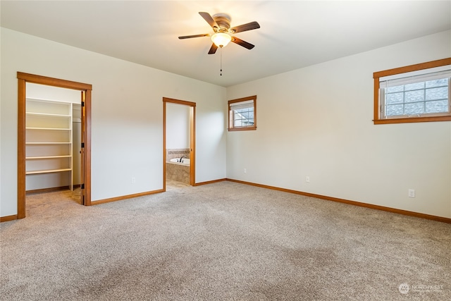 unfurnished bedroom with a walk in closet, ceiling fan, light colored carpet, and multiple windows