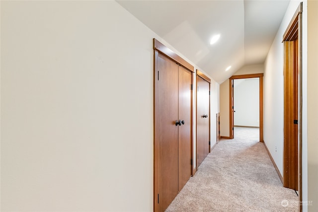 hall with light colored carpet and lofted ceiling