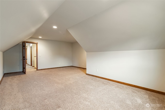 bonus room with light carpet and vaulted ceiling