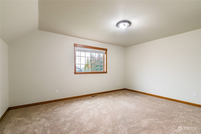 spare room featuring carpet floors and vaulted ceiling