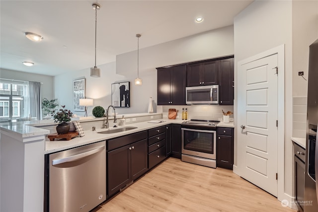 kitchen featuring sink, appliances with stainless steel finishes, kitchen peninsula, and pendant lighting