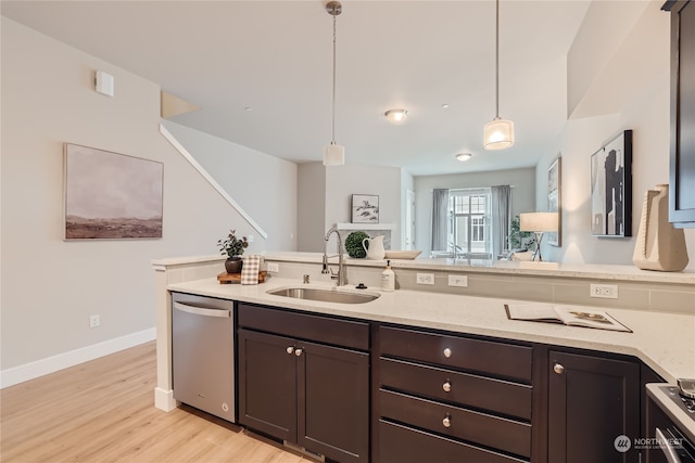 kitchen with hanging light fixtures, light stone countertops, stainless steel appliances, light hardwood / wood-style floors, and sink