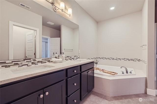 bathroom with vanity, a relaxing tiled tub, and tile patterned floors