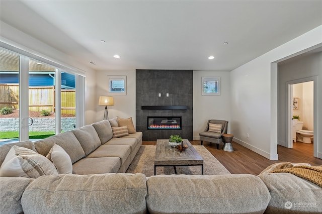 living room featuring a tiled fireplace and light wood-type flooring