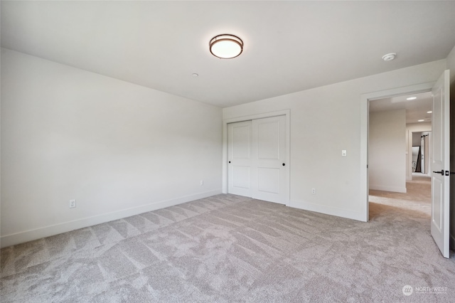 unfurnished bedroom featuring a closet and light colored carpet