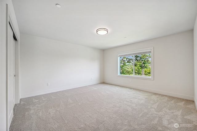 unfurnished bedroom with light carpet and a closet