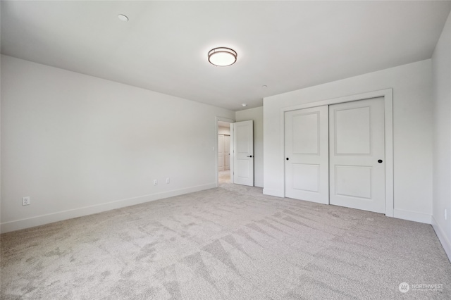 unfurnished bedroom with light colored carpet and a closet