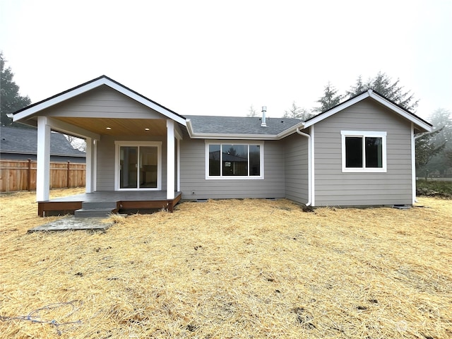 back of property with a deck and a lawn