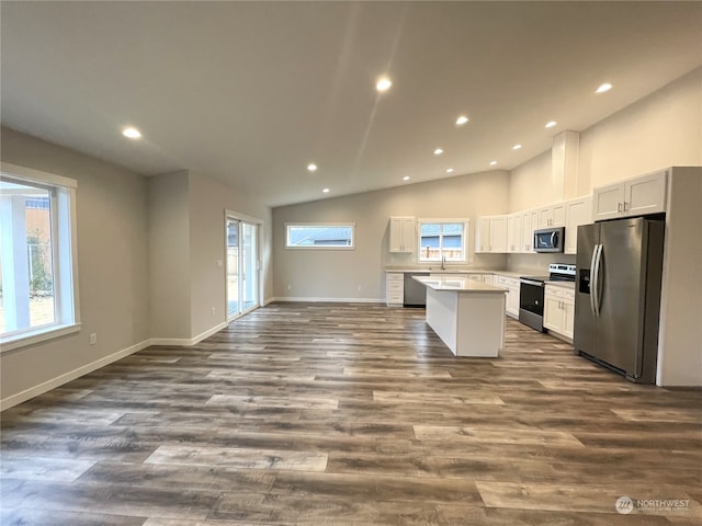 kitchen with a kitchen island, vaulted ceiling, white cabinetry, appliances with stainless steel finishes, and dark hardwood / wood-style flooring