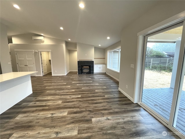 unfurnished living room featuring dark hardwood / wood-style flooring, an AC wall unit, a fireplace, and vaulted ceiling