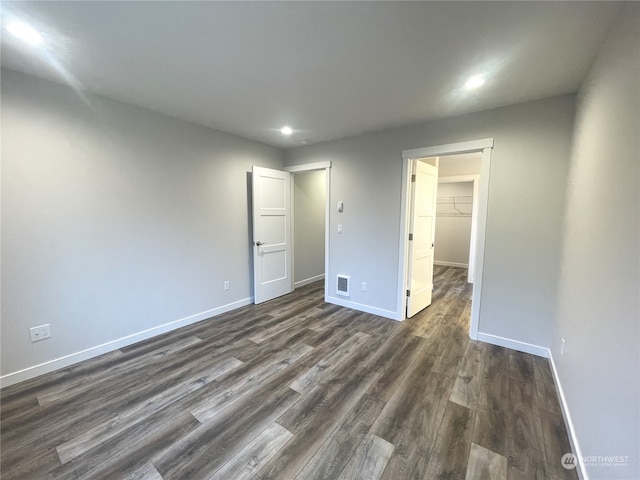 unfurnished bedroom featuring a walk in closet, dark hardwood / wood-style floors, and a closet