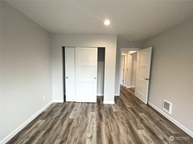 unfurnished bedroom with dark wood-type flooring and a closet