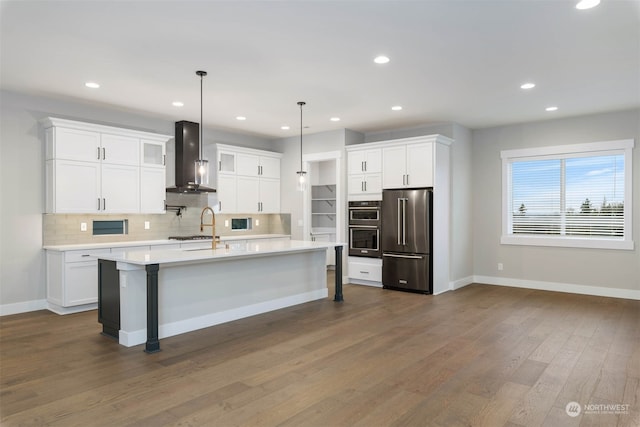 kitchen with wall chimney range hood, white cabinetry, stainless steel appliances, pendant lighting, and dark hardwood / wood-style floors