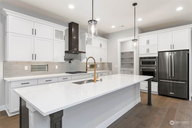 kitchen with wall chimney range hood, white cabinets, dark hardwood / wood-style flooring, appliances with stainless steel finishes, and decorative light fixtures