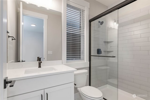 bathroom featuring toilet, walk in shower, and vanity