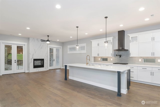 kitchen featuring wall chimney range hood, white cabinetry, hanging light fixtures, and dark hardwood / wood-style floors