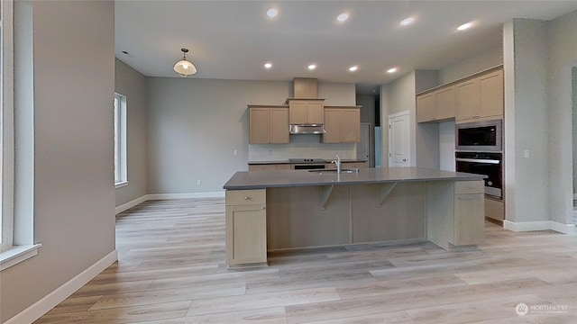 kitchen featuring built in microwave, sink, a center island with sink, oven, and light hardwood / wood-style floors