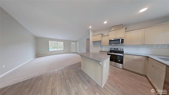 kitchen featuring lofted ceiling, appliances with stainless steel finishes, light hardwood / wood-style floors, and decorative backsplash