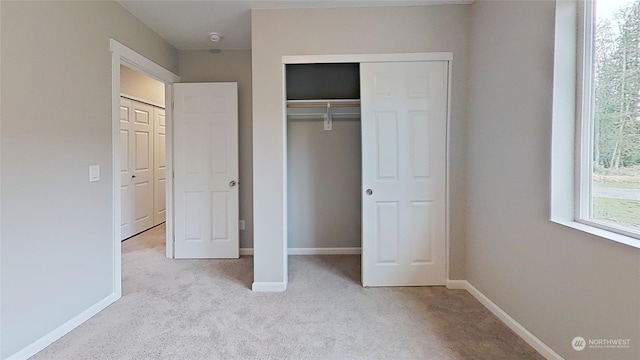 unfurnished bedroom with light colored carpet and a closet