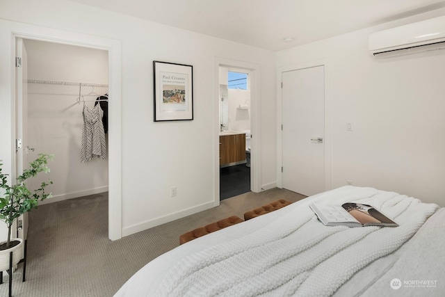 bedroom with ensuite bathroom, carpet flooring, a wall mounted air conditioner, a walk in closet, and a closet