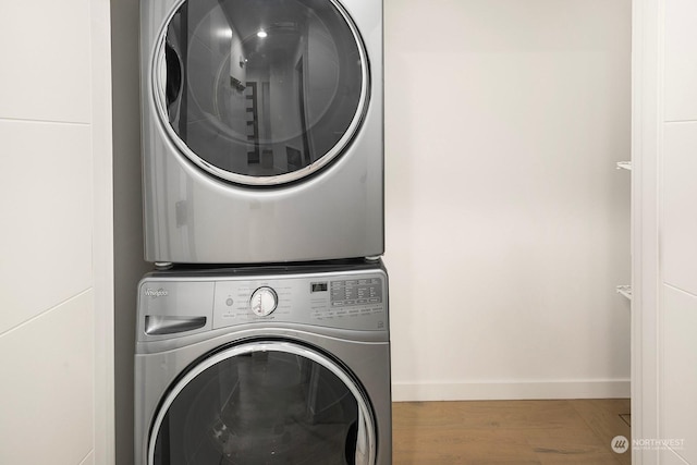 laundry room featuring hardwood / wood-style flooring and stacked washer / drying machine