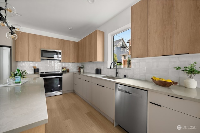 kitchen featuring light wood-type flooring, appliances with stainless steel finishes, decorative backsplash, sink, and white cabinets