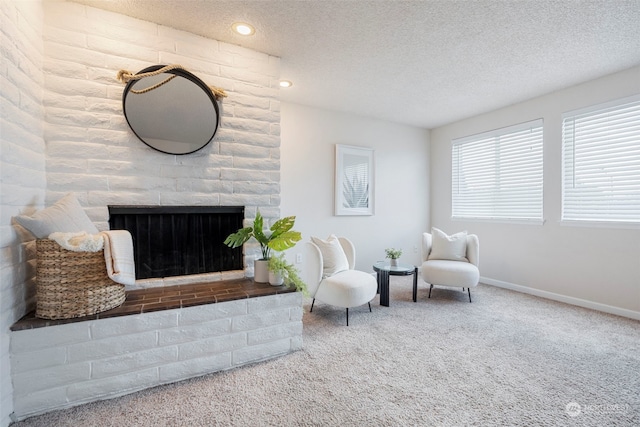 sitting room featuring a textured ceiling, carpet, and a brick fireplace