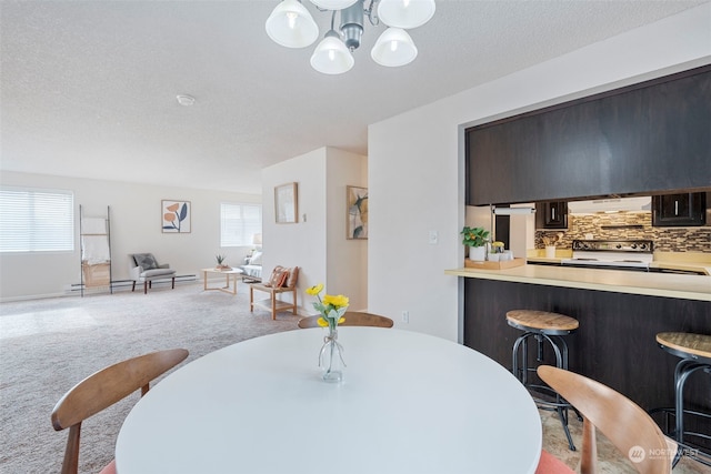 carpeted dining room featuring a chandelier, a textured ceiling, and a healthy amount of sunlight