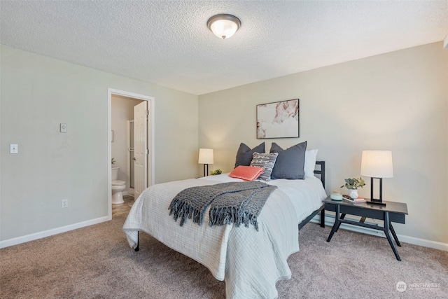 carpeted bedroom with ensuite bath and a textured ceiling