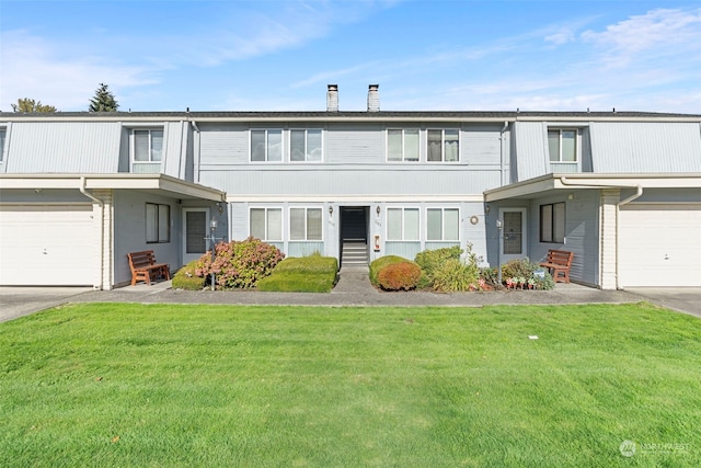 multi unit property featuring a front lawn and a garage