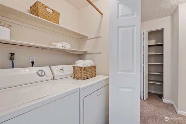 laundry area featuring washer and dryer, a textured ceiling, and light colored carpet