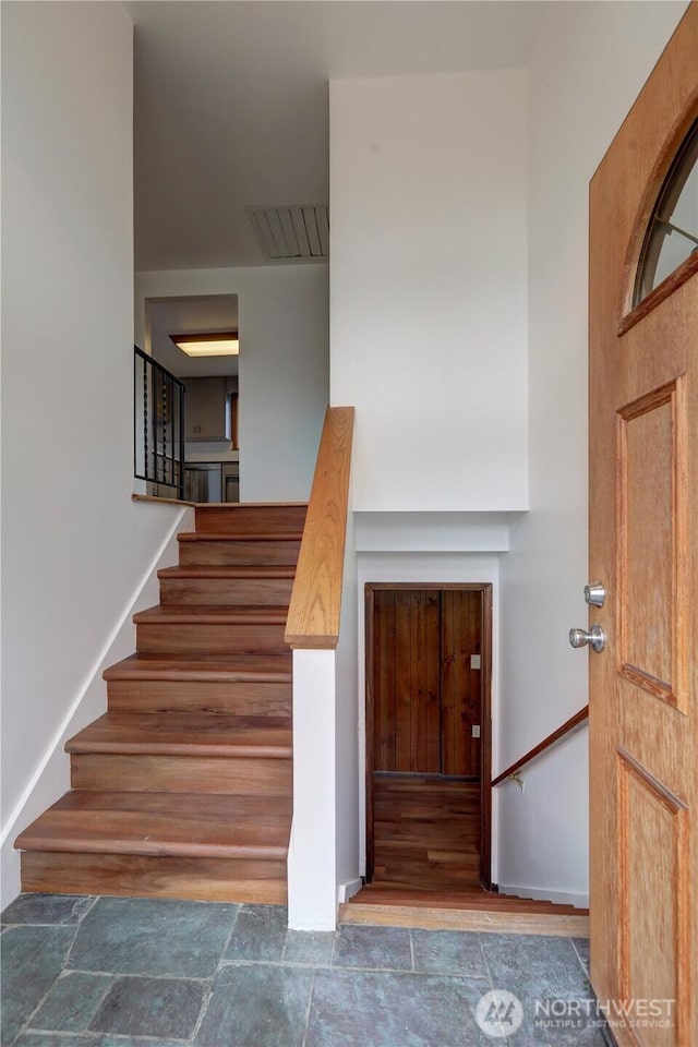 staircase with stone finish floor, baseboards, and visible vents