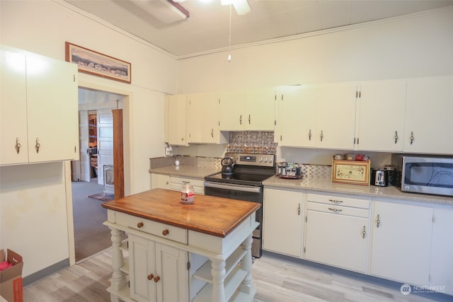 kitchen with appliances with stainless steel finishes, crown molding, white cabinets, and light hardwood / wood-style floors