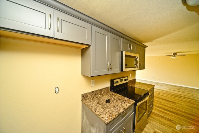 kitchen featuring light hardwood / wood-style flooring, stainless steel appliances, dark stone counters, gray cabinets, and ceiling fan