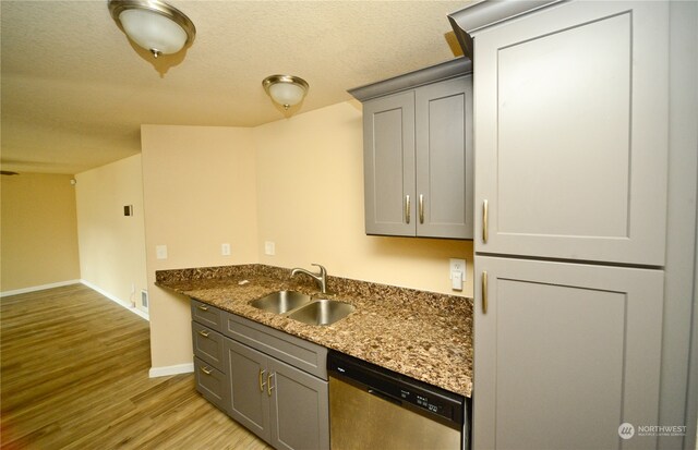 kitchen featuring dark stone counters, sink, light wood-type flooring, gray cabinets, and stainless steel dishwasher