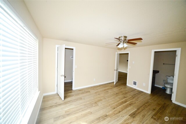 unfurnished bedroom with ceiling fan, light wood-type flooring, and ensuite bath