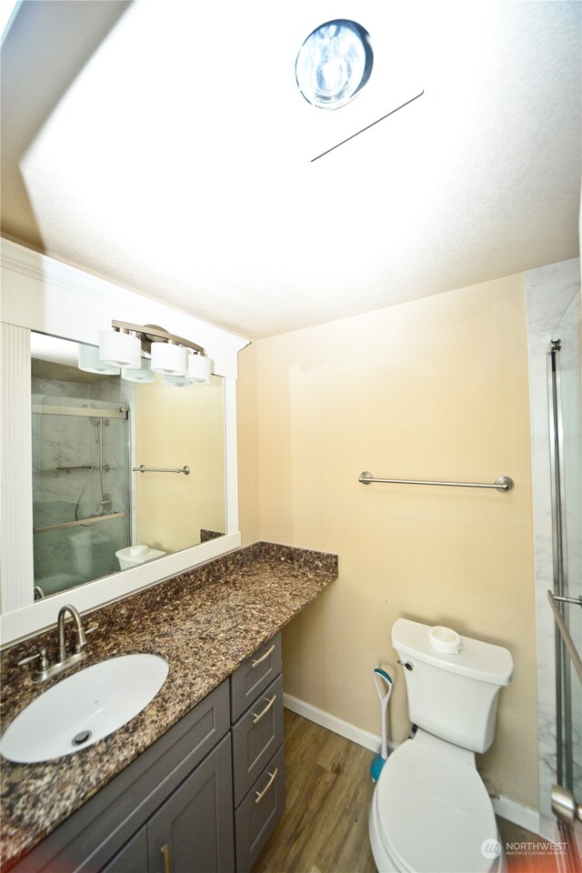 bathroom featuring vanity, wood-type flooring, toilet, and walk in shower