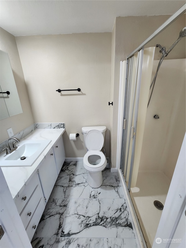 bathroom with a shower stall, baseboards, toilet, marble finish floor, and vanity