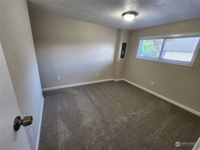 empty room with electric panel, a textured ceiling, baseboards, and dark colored carpet