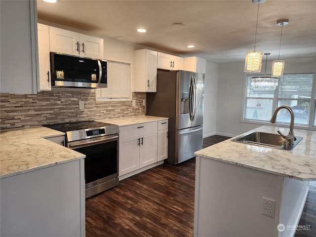 kitchen with a sink, dark wood-type flooring, appliances with stainless steel finishes, decorative light fixtures, and tasteful backsplash