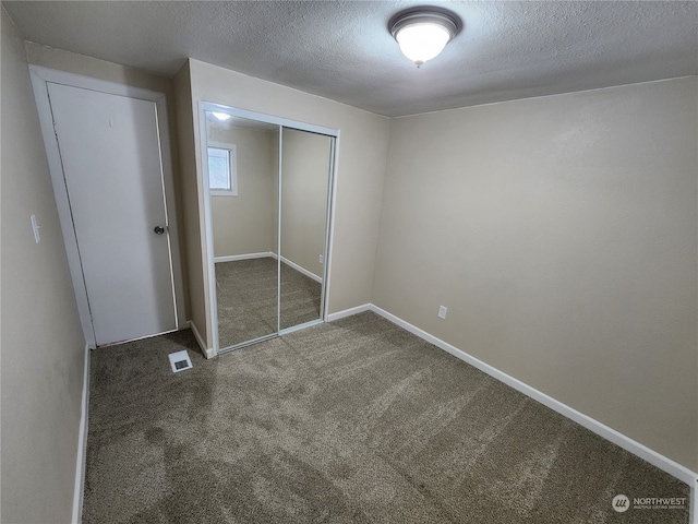 unfurnished bedroom featuring visible vents, baseboards, carpet floors, a closet, and a textured ceiling