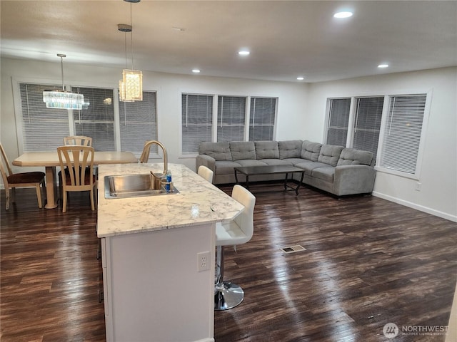 kitchen with a sink, visible vents, a kitchen island with sink, and dark wood finished floors