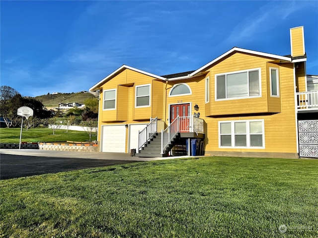 raised ranch with a front lawn and a garage