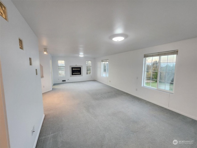 151 Rilla Ln, Sequim, WA 98382 - unfurnished living room with carpet floors, baseboards, and a glass covered fireplace